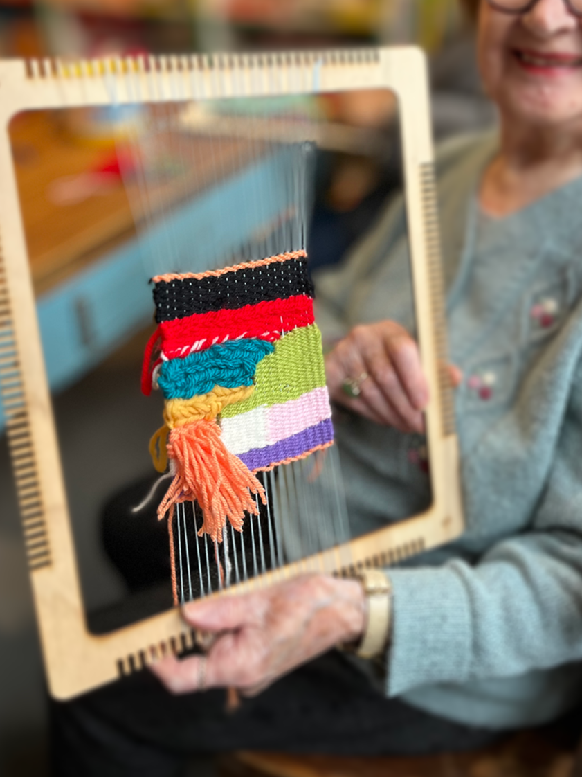 Two students weaving patterned textile strips